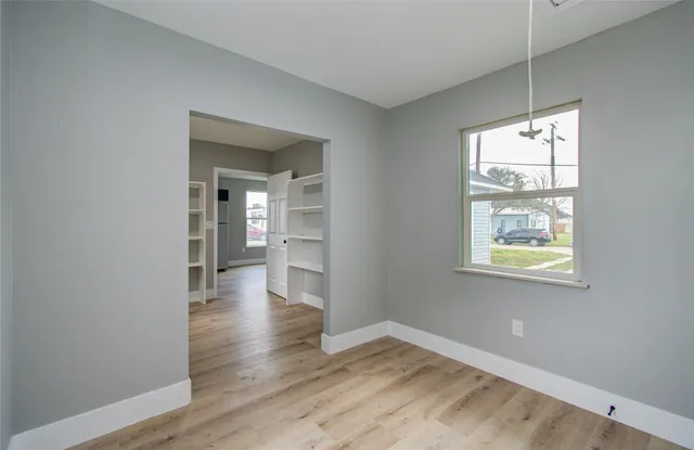 a view of an empty room with wooden floor and a window