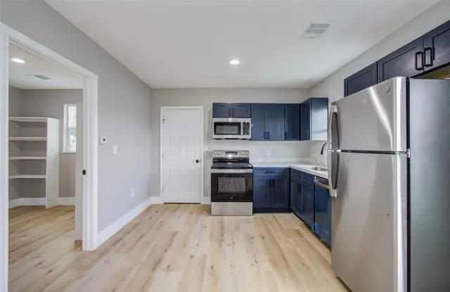 a kitchen with a refrigerator a stove top oven and wooden floor