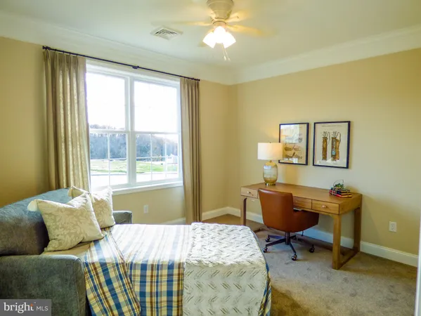 a bedroom with a bed a desk and chair with a window
