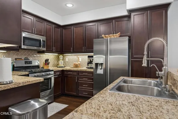 a kitchen with stainless steel appliances granite countertop a sink stove and refrigerator