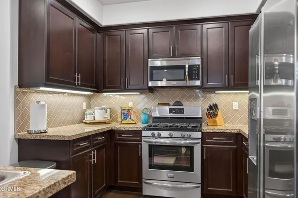 a kitchen with granite countertop wooden cabinets and stainless steel appliances