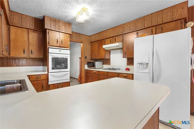 a large white kitchen with a sink and refrigerator