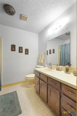a bathroom with a granite countertop sink mirror vanity and toilet