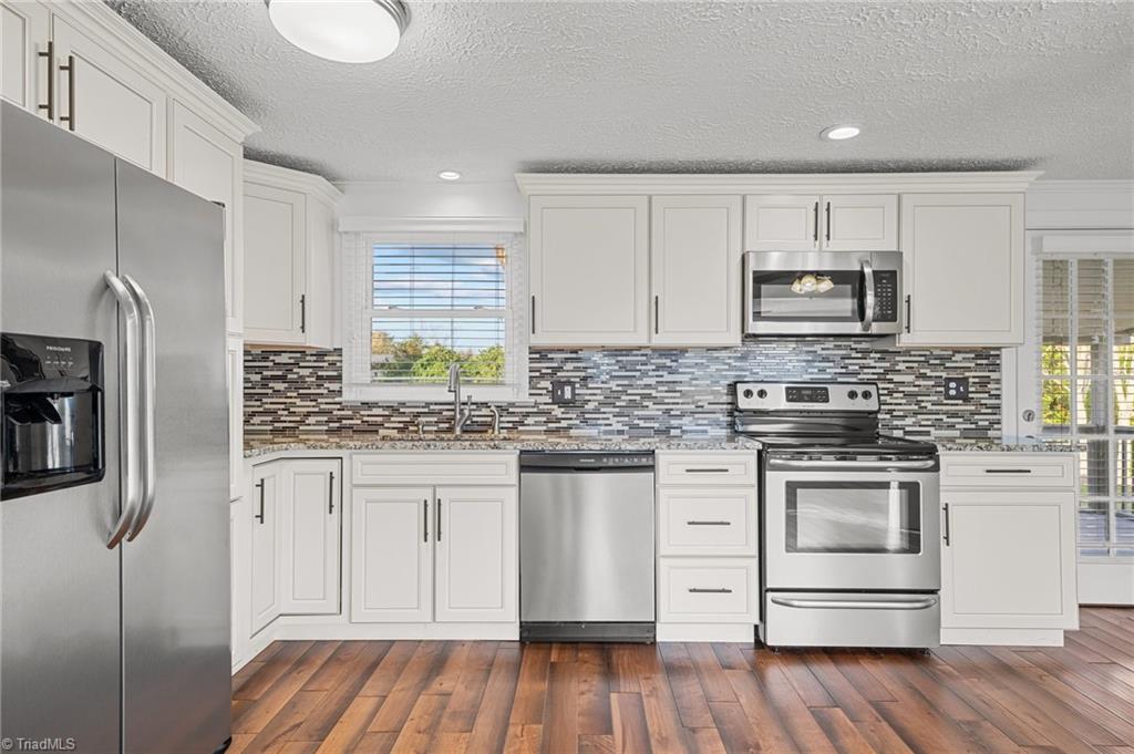 8440 West Harrell Road Oak Ridge, NC 27310 - Photo 3 of 50 SS appliances and newer cabinets, granite counters and tile backsplash