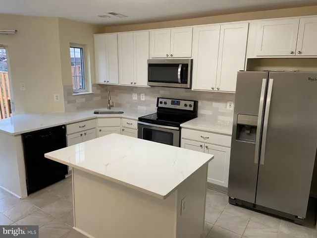 a kitchen with a sink a microwave a refrigerator and cabinets