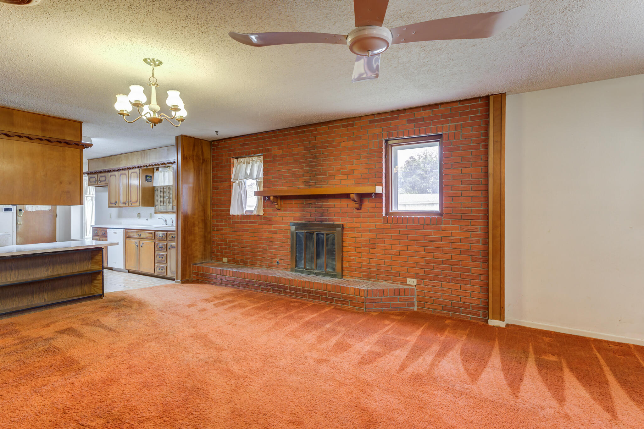 5502 8th Street Lubbock, TX 79416 - Photo 7 of 37 a view of a livingroom with a fireplace a chandelier fan and windows