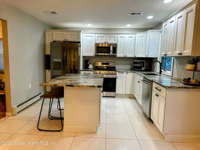 a kitchen with kitchen island granite countertop a stove top oven a sink a counter top space and cabinets