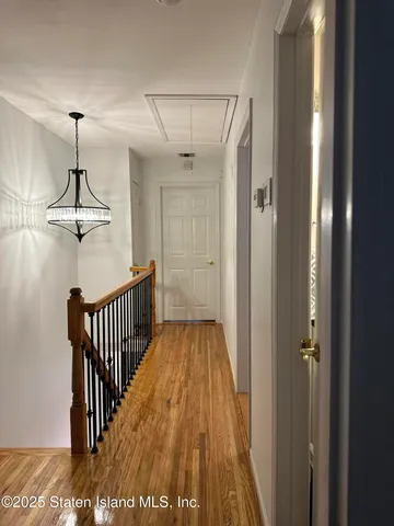 a view of hallway with wooden floor and chandelier