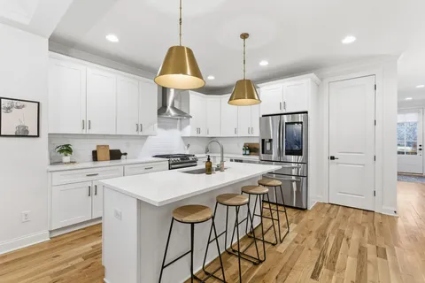 a kitchen with a sink a stove a refrigerator and white cabinets