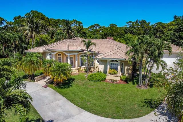 a view of a white house with a yard table and chairs