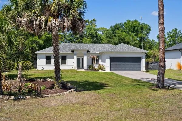 a view of a house with a yard and large tree