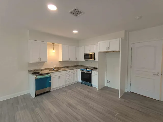 a large kitchen with cabinets wooden floor and stainless steel appliances