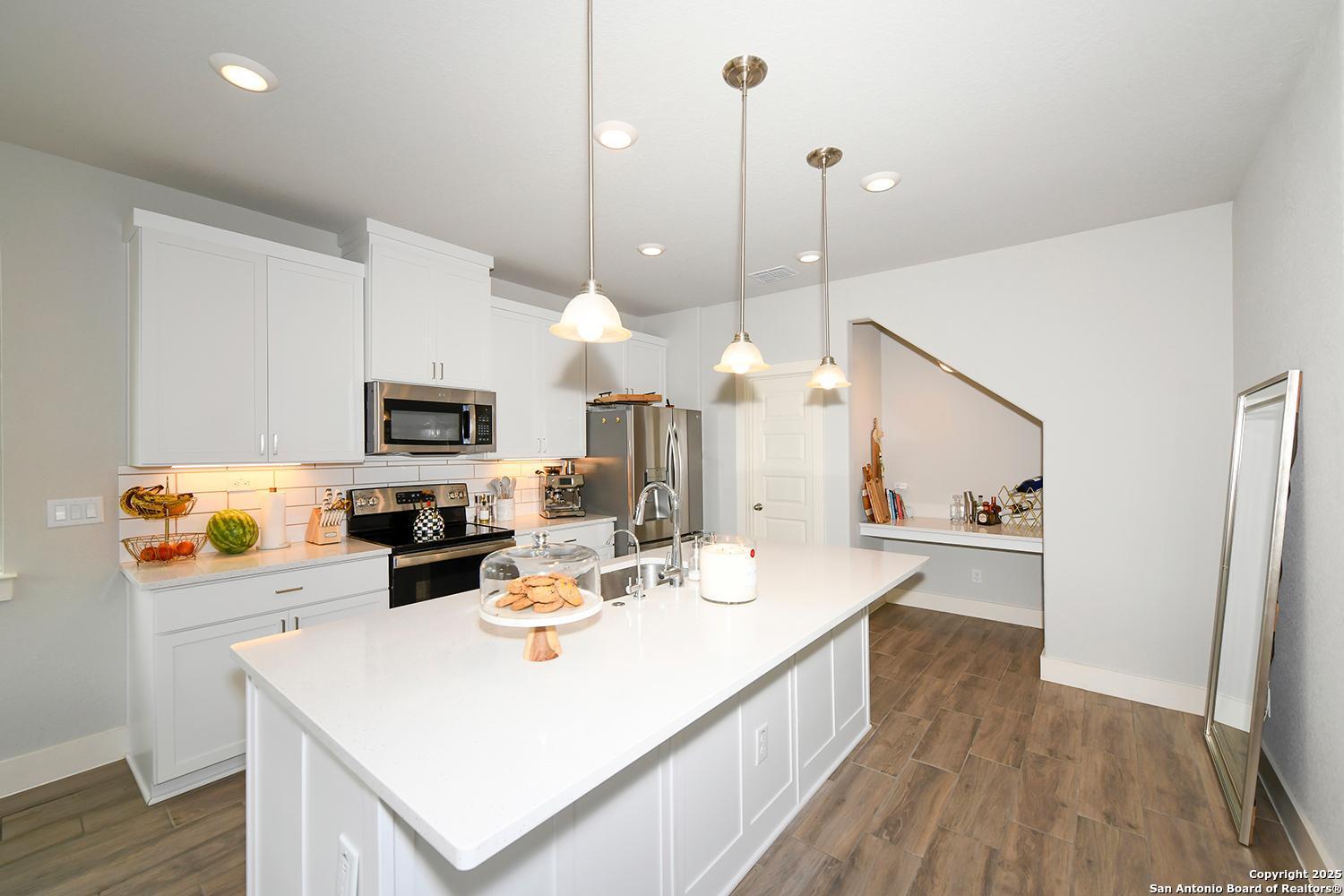 16011 Babcock Road, Unit 13 San Antonio, TX 78255 - Photo 8 of 25 a kitchen with kitchen island a white counter top space stainless steel appliances and wooden floor