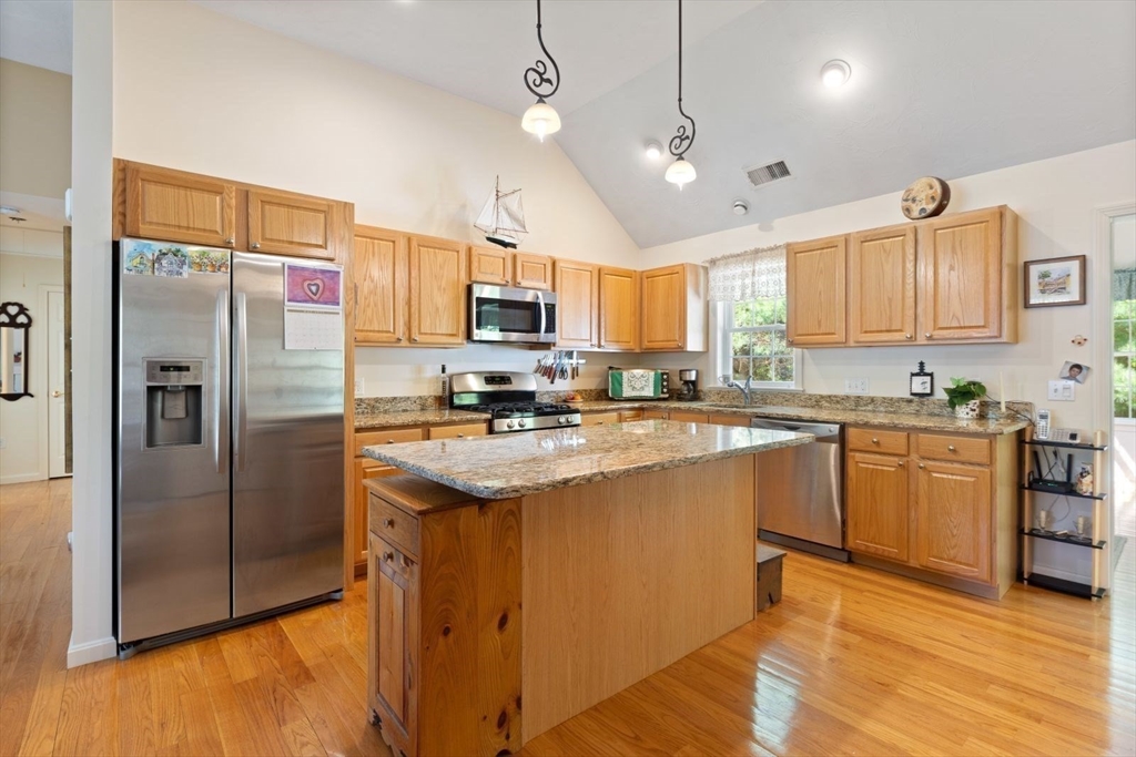 60 Brewster Road, Unit 60 Stoughton, MA 02072 - Photo 5 of 18 a kitchen with stainless steel appliances granite countertop a refrigerator a sink dishwasher a stove top oven a kitchen island and chairs with wooden floor