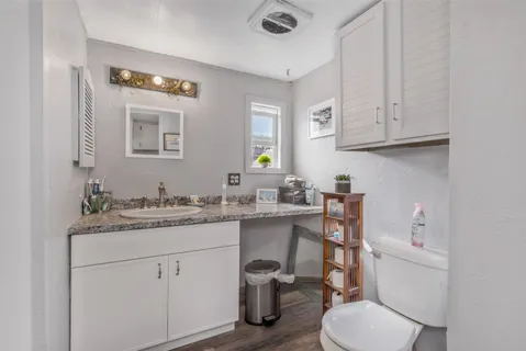 a bathroom with a granite countertop toilet sink and mirror