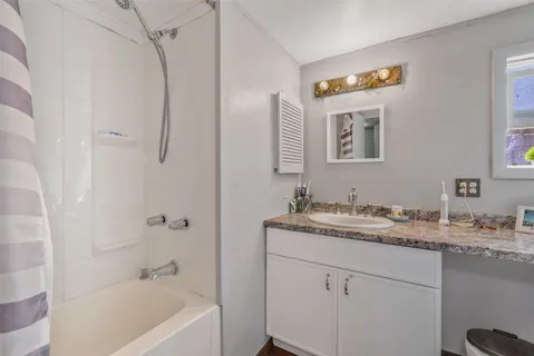 a bathroom with a granite countertop sink a mirror a vanity and a bathtub