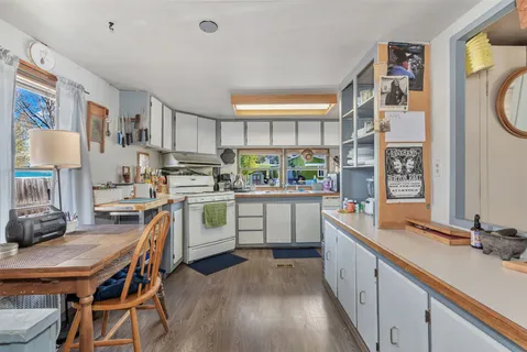 a kitchen with white cabinets and wooden floor