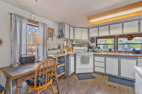 a open kitchen with stainless steel appliances granite countertop a stove top oven a sink dishwasher and white cabinets with wooden floor