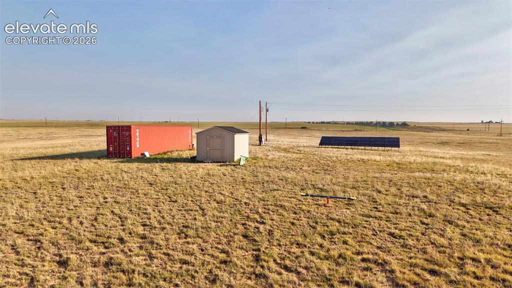 9670 Boone Road Yoder, CO 80864 - Photo 14 of 18 Expansive open land featuring a red storage container, a utility shed, and ground-mounted solar panels