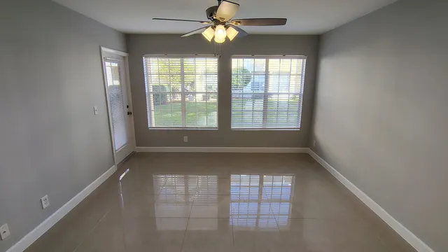 an empty room with windows and ceiling fan