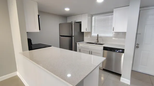 a kitchen with a refrigerator a stove a sink a washer dryer and white cabinets