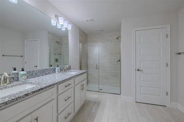 a bathroom with a granite countertop sink a mirror and a shower
