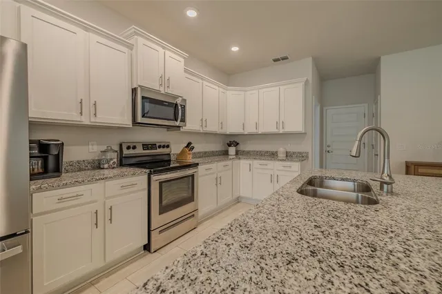a kitchen with stainless steel appliances kitchen island granite countertop a sink a stove a dining table and chairs