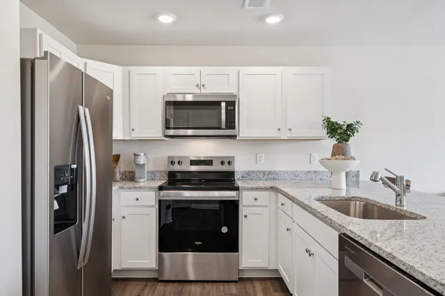 a kitchen with stainless steel appliances granite countertop a sink a stove and a wooden cabinets
