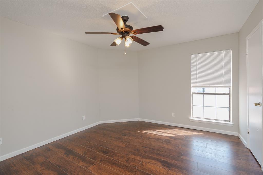 2821 Wimbledon Court Garland, TX 75041 - Photo 18 of 27 an empty room with wooden floor fan and windows