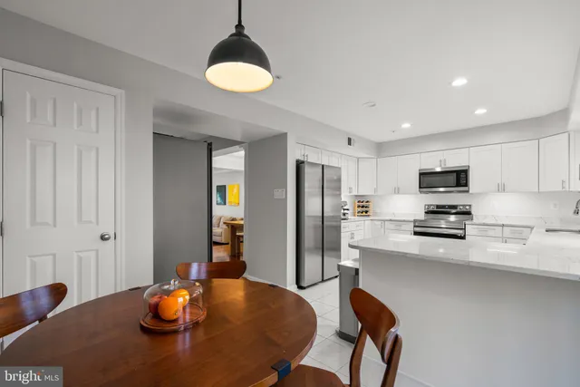 a kitchen with stainless steel appliances granite countertop a dining table and chairs with wooden floor