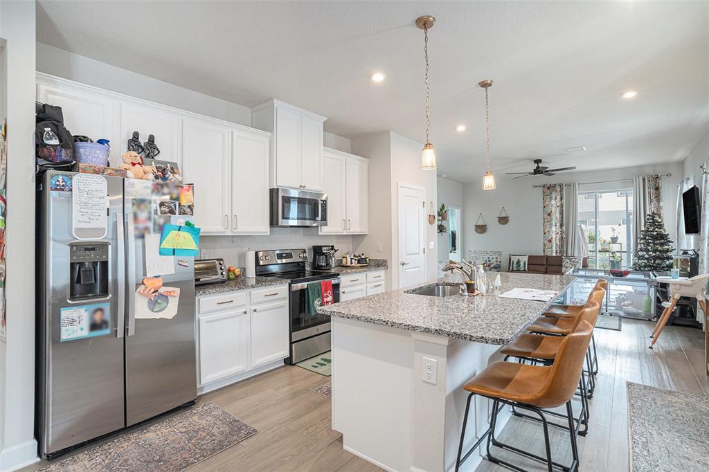 19056 Heavenside Ct Spring Hill Spring Hill, FL 34610 - Photo 7 of 25 a kitchen with stainless steel appliances granite countertop a refrigerator a stove top oven a sink dishwasher and white cabinets with wooden floor