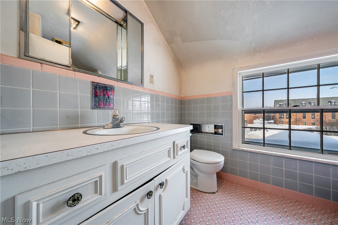 4602 College Road South Euclid, OH 44121 - Photo 21 of 26 Half bathroom featuring vanity, tile walls, vaulted ceiling, and light tile patterned flooring