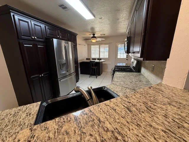 a kitchen with granite countertop a refrigerator stove and sink