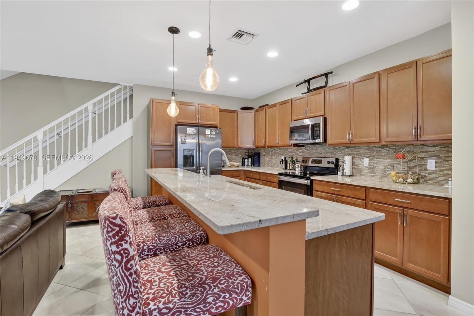 5208 Falcon Trail Davie, FL 33314 - Photo 15 of 49 a kitchen with stainless steel appliances granite countertop a stove a sink dishwasher a microwave oven and a refrigerator with wooden cabinets