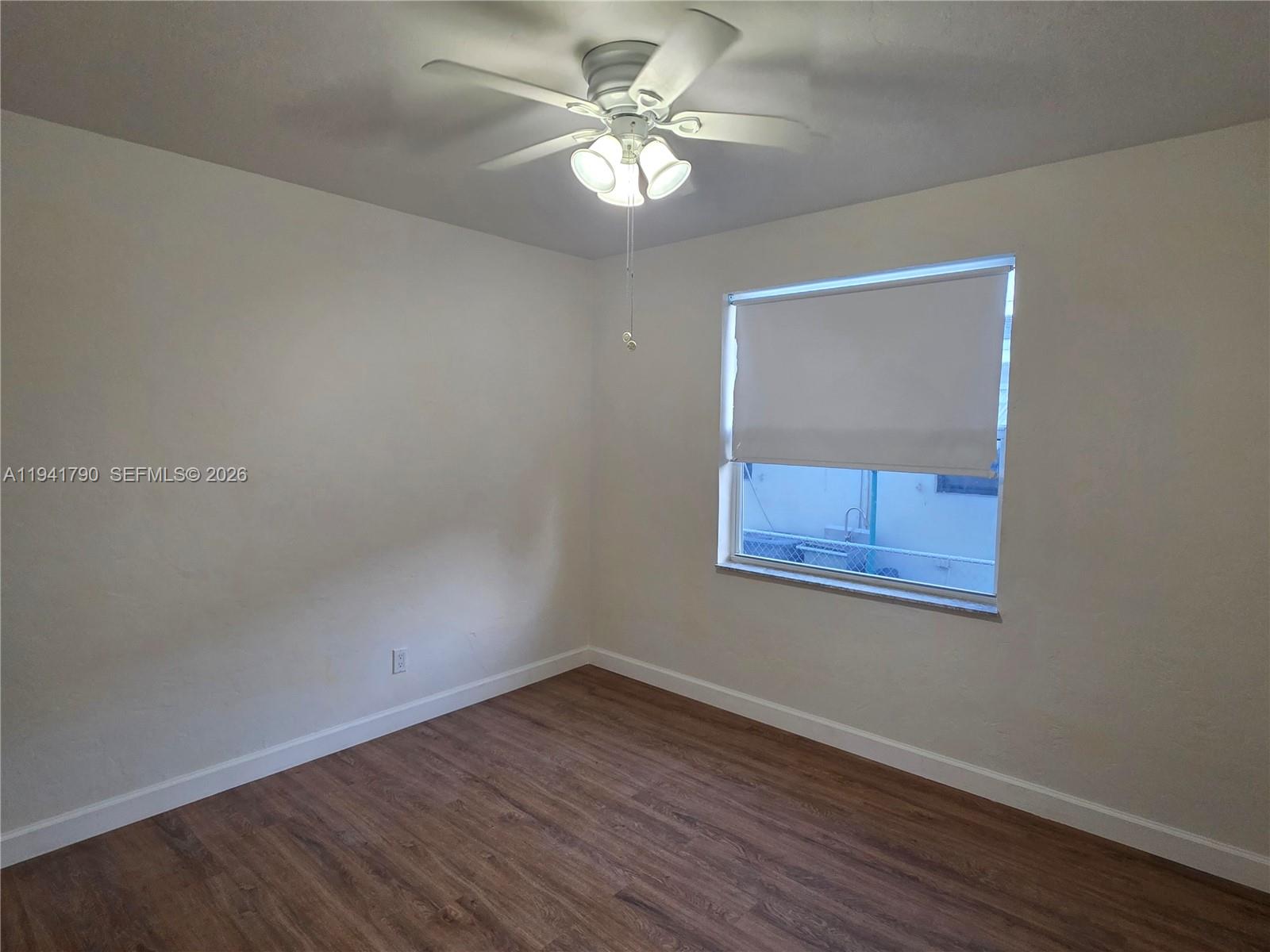 4310 East 9th Lane Hialeah, FL 33013 - Photo 17 of 21 a view of an empty room with a window and wooden floor