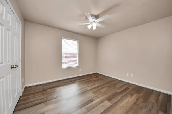 a view of an empty room with wooden floor and a window