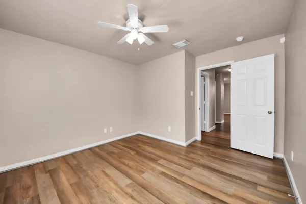 an empty room with wooden floor and ceiling fan