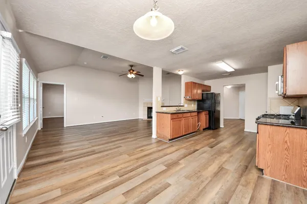 a large kitchen with stainless steel appliances kitchen island a large counter top and wooden floors