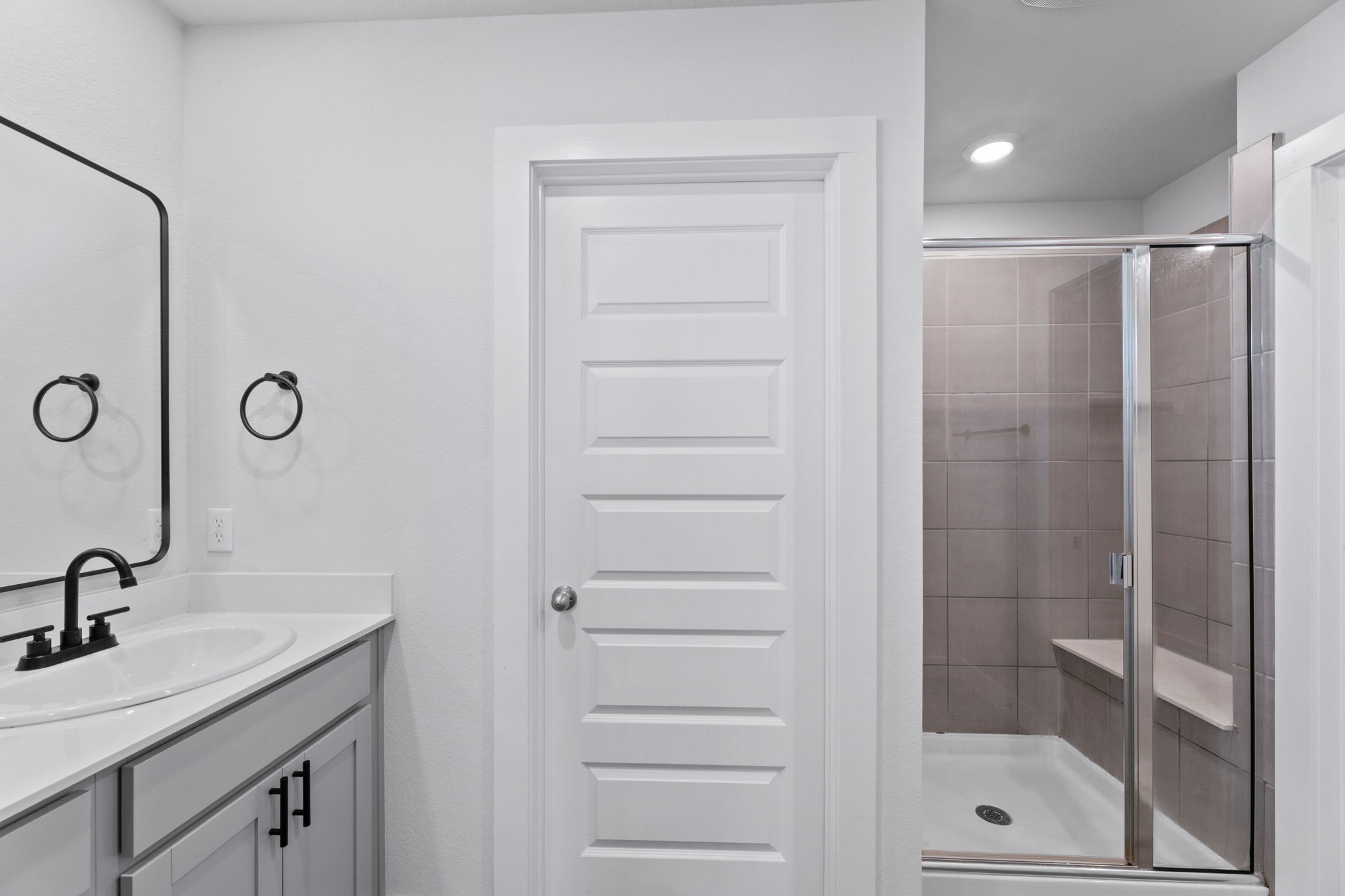 7312 Travertine Spring Drive Austin, TX 78744 - Photo 20 of 32 A well-appointed bath features a sleek vanity and a tiled walk-in shower with a convenient built-in bench.