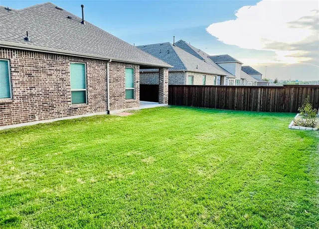 a view of a house with backyard and wooden fence