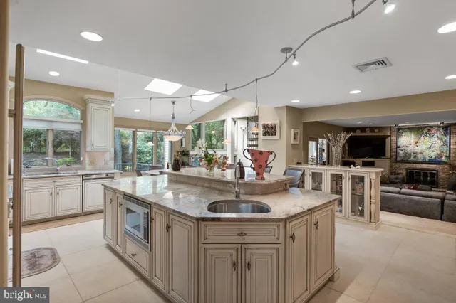 a dining hall with stainless steel appliances kitchen island granite countertop a table chairs and a view of living room