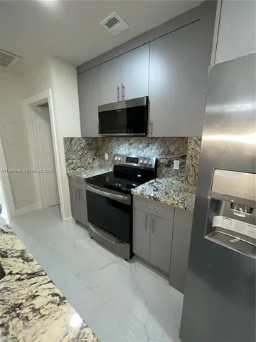 a kitchen with stainless steel appliances granite countertop a sink a stove and a refrigerator