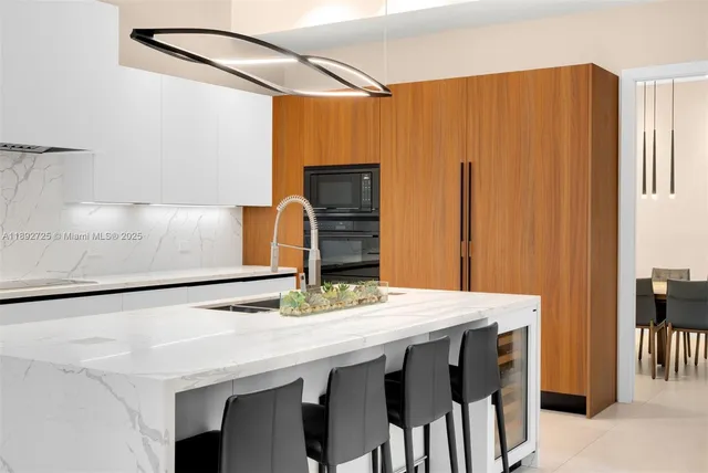 a large white kitchen with kitchen island a sink stainless steel appliances and cabinets