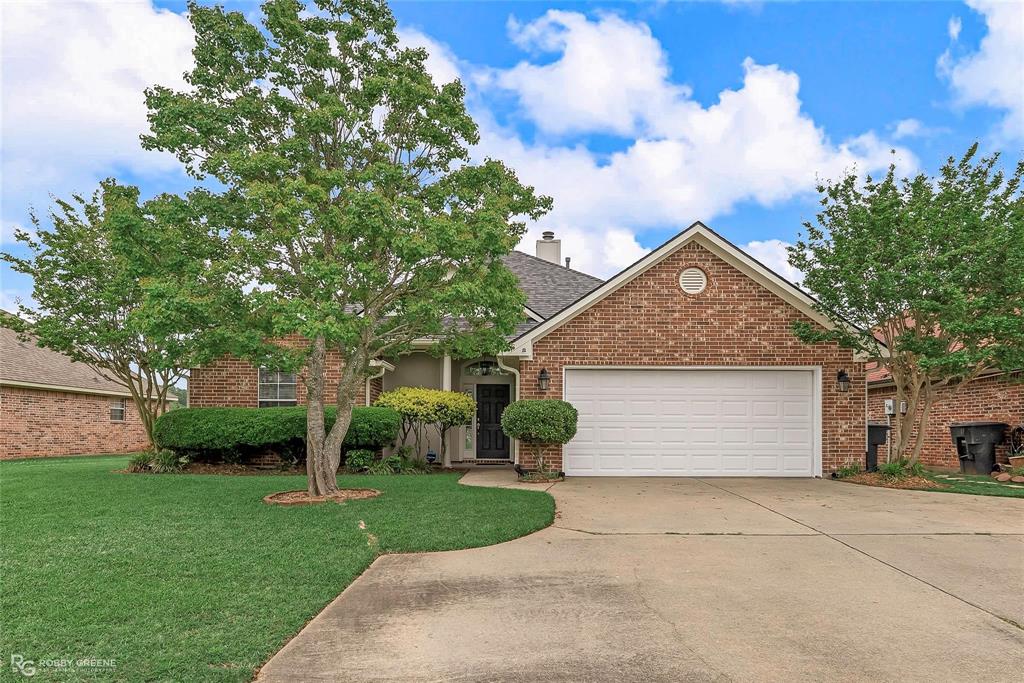 View of front of property featuring a garage, a front lawn, brick siding, and concrete driveway