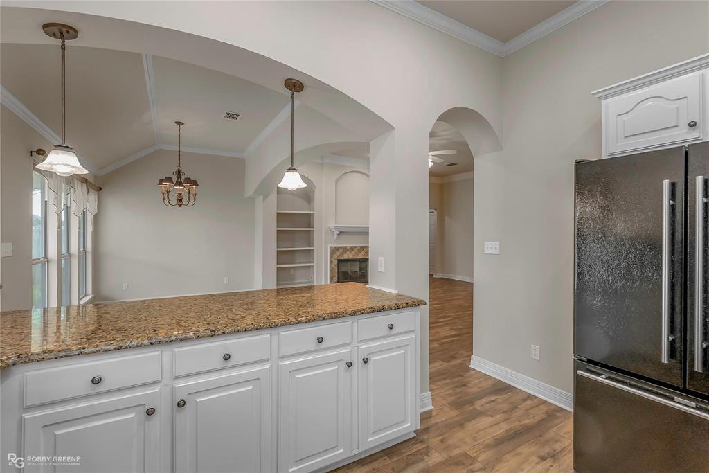 2186 Stockwell Road Bossier City, LA 71111 - Photo 11 of 40 Kitchen with ornamental molding, white cabinetry, freestanding refrigerator, light stone countertops, and a fireplace