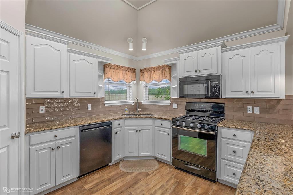 2186 Stockwell Road Bossier City, LA 71111 - Photo 13 of 40 Kitchen with black appliances, ornamental molding, white cabinets, decorative backsplash, and light stone countertops