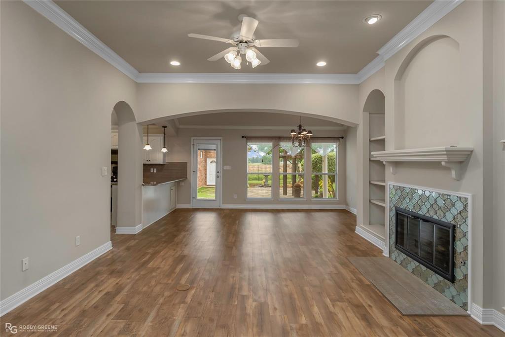 2186 Stockwell Road Bossier City, LA 71111 - Photo 9 of 40 Unfurnished living room featuring ceiling fan, built in features, suspended lighting, dark wood-type flooring, and crown molding