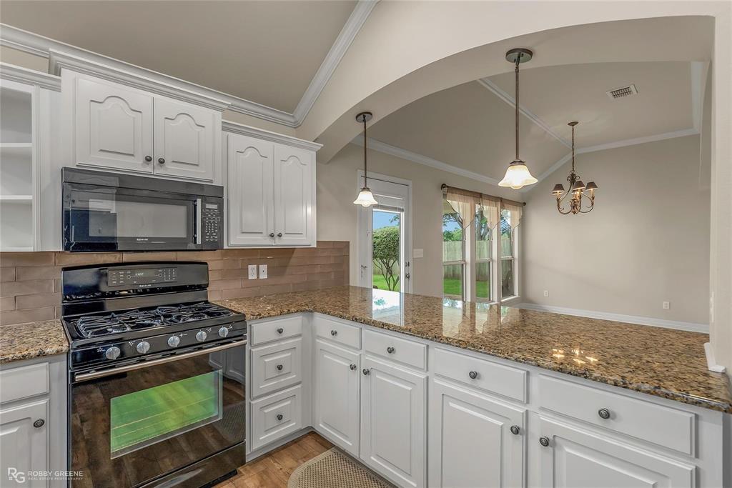2186 Stockwell Road Bossier City, LA 71111 - Photo 10 of 40 Kitchen with black appliances, white cabinetry, dark stone countertops, backsplash, and vaulted ceiling