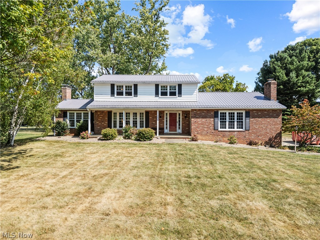 3650 Rambo Avenue Alliance, OH 44601 - Photo 1 of 36 Brick and siding exterior with a metal roof, featuring a covered front porch, multiple windows with shutters, and mature trees