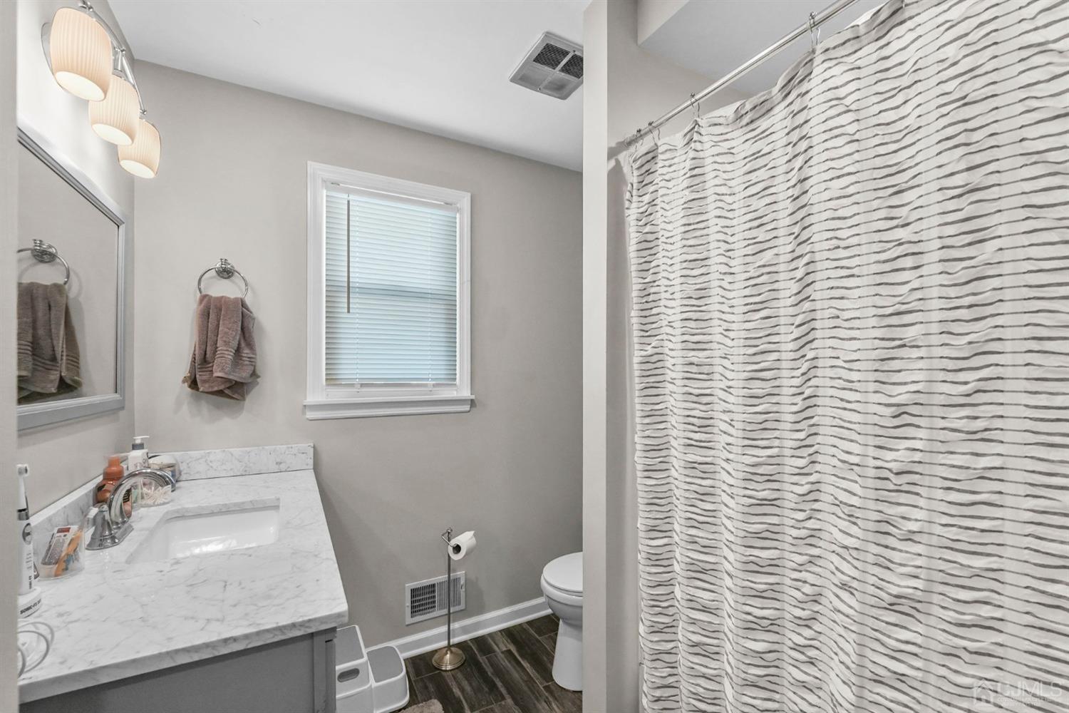 1067 Riverton Street North Brunswick, NJ 08902 - Photo 14 of 45 a bathroom with a sink a toilet and shower curtain